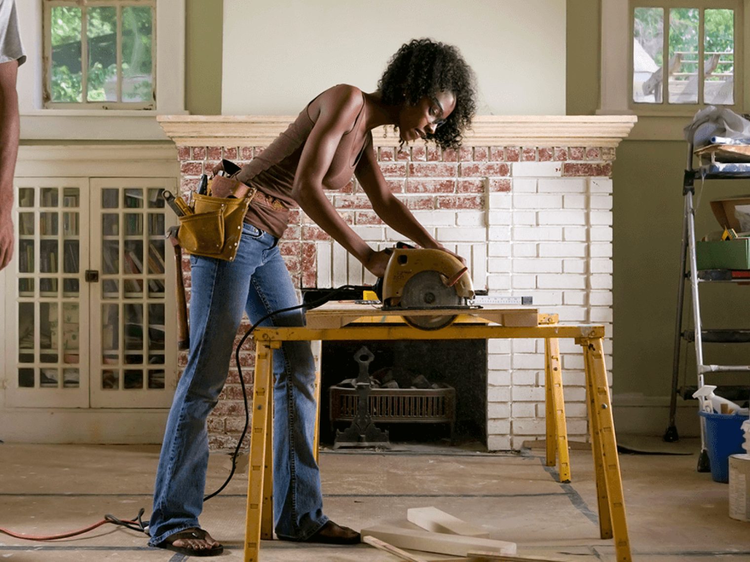 Woman using an electric saw while doing renovations in her home.