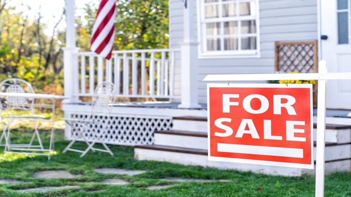 Red For Sale sign in front of a white house.