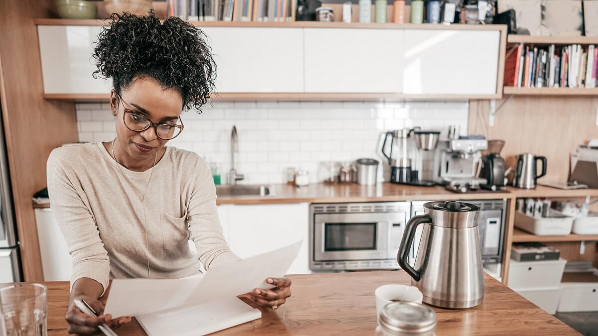 Woman budgets at kitchen island.